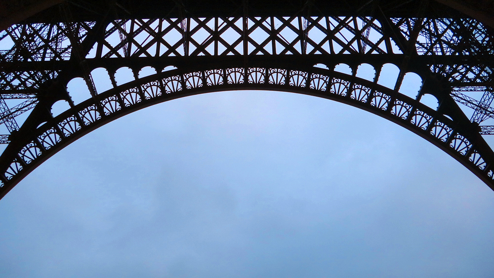 Underneath arch of black metal bridge