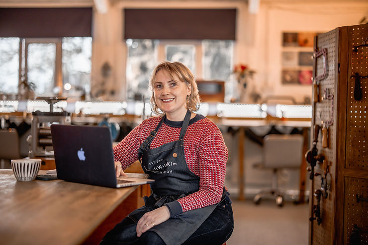 Picture of Kim sitting at a work bench with her laptop