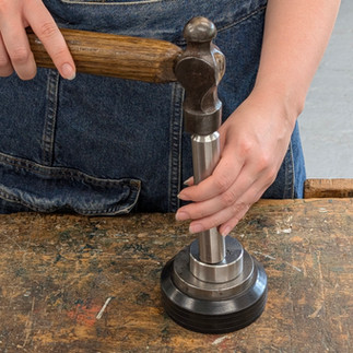 hammering a steel rod to pin metal