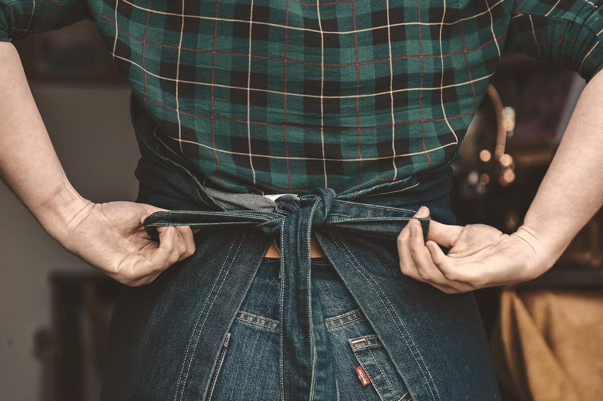 Person tying denim apron behind their back