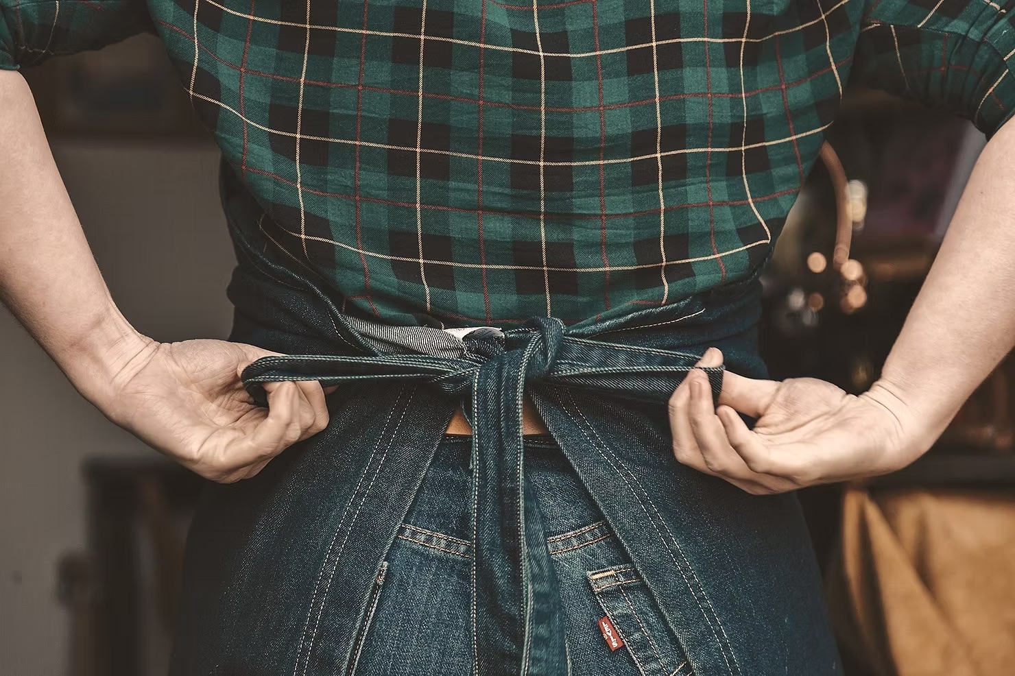 Person tying denim apron behind their back