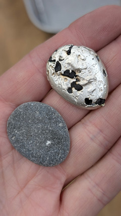Pebble necklace pendant next to pebble