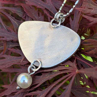 Silver back of necklace over seaweed