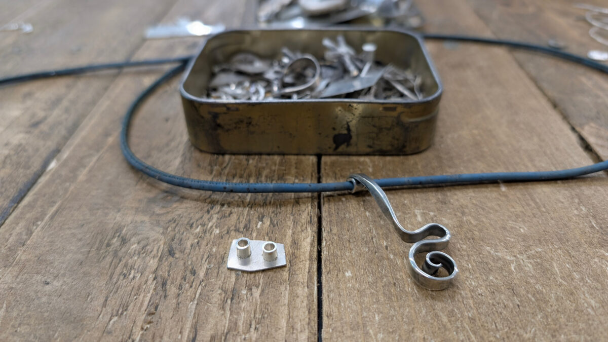 two silver end caps and silver hand forged scroll pendant on bamboo thonging