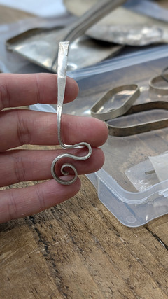 silver hand forged scroll pendant in hand